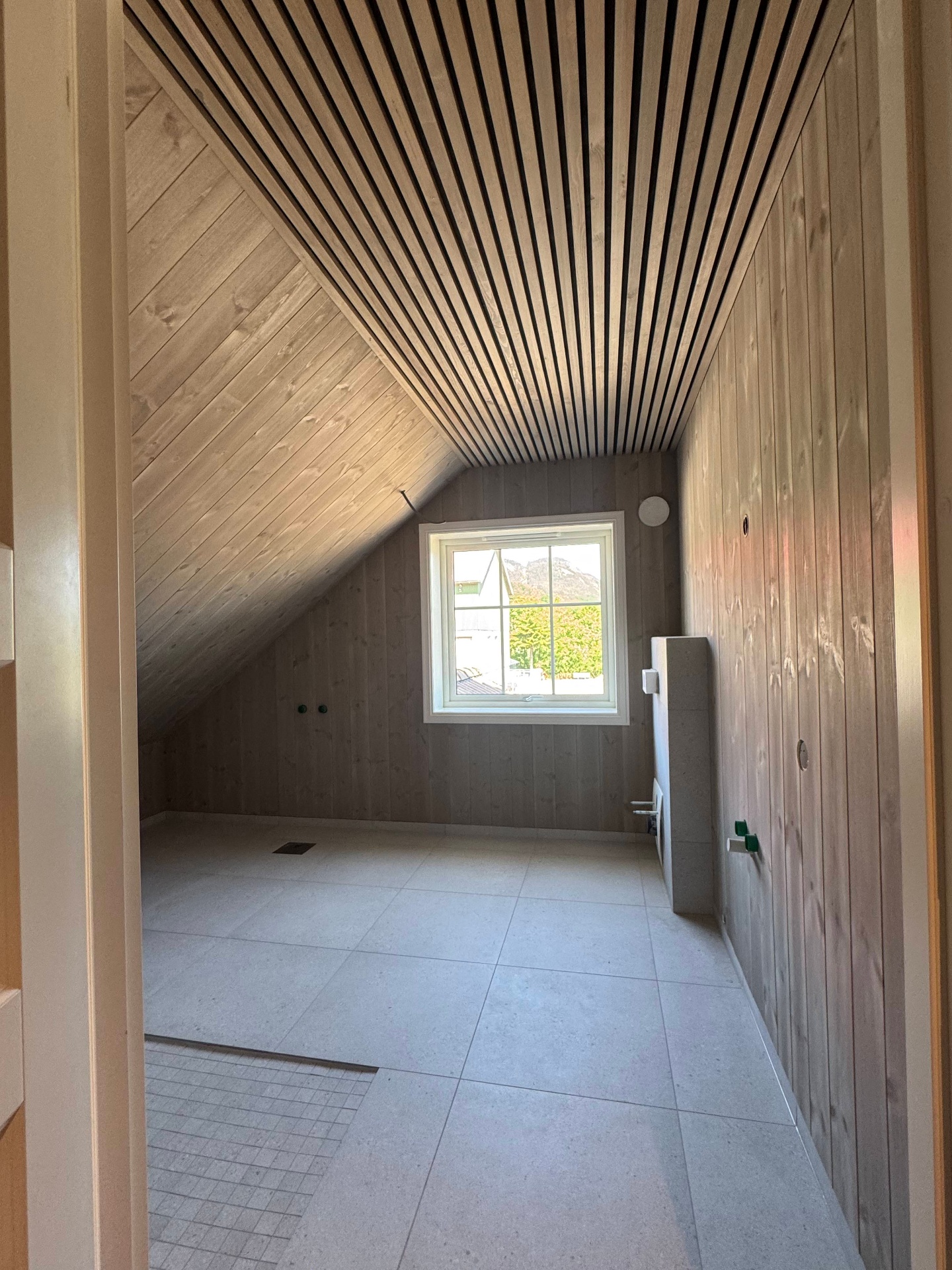 Ferdig loftsbad med spilepanel i taket og lyse fliser, utført av Danielsen Bygg AS